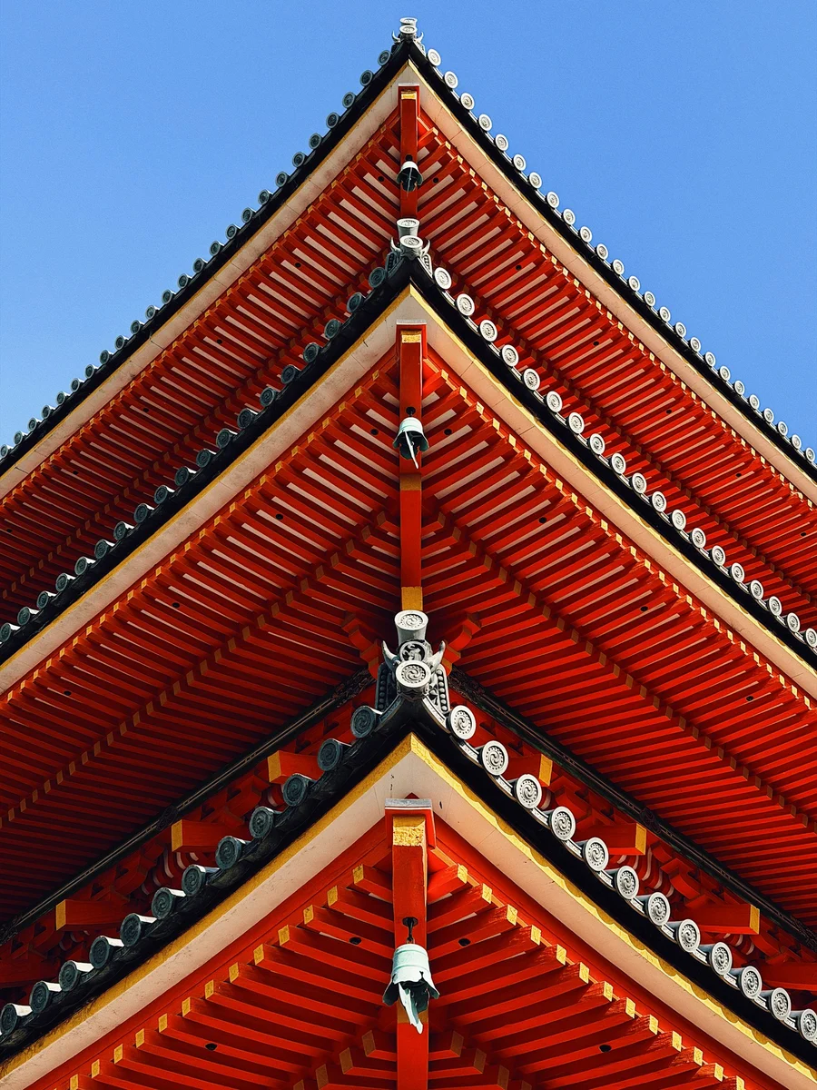 Red pagoda roof at Kiyomizu-dera in Kyoto against a blue sky